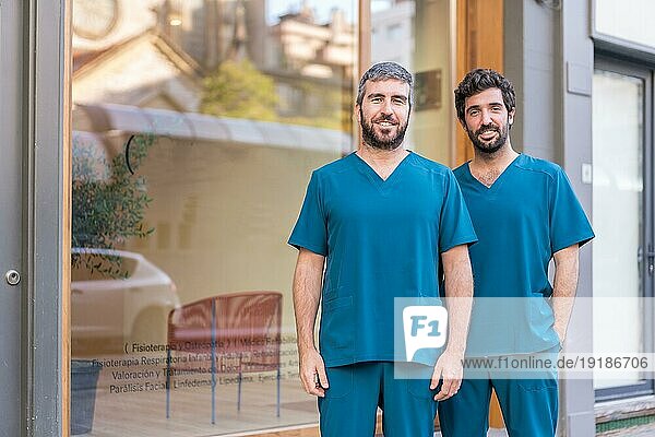 Horizontales Porträt eines fröhlichen medizinischen Teams  das im Eingang einer Klinik steht