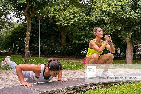 Latino Mädchen beim Sport in einem Park in der Stadt  Lifestyle ein gesundes Leben  zwei Mädchen tun Stretching und Kniebeugen