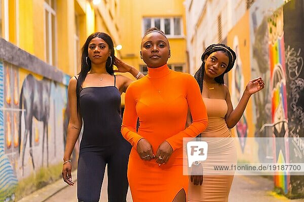 San Sebastián  Gipuzkoa Spanien  Februar 2021: Modischer urbaner Stil mit drei schwarzafrikanischen Mädchen auf einer Stadtstraße  enge Kleider und verführerische Looks. Lifestyle Girls of Color