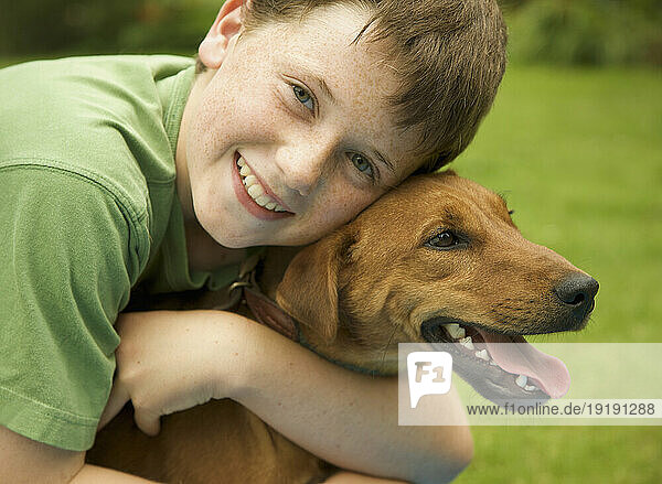 Young smiling boy embracing his dog
