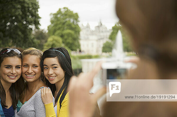 Back view of a woman taking photograph of three teenaged girls
