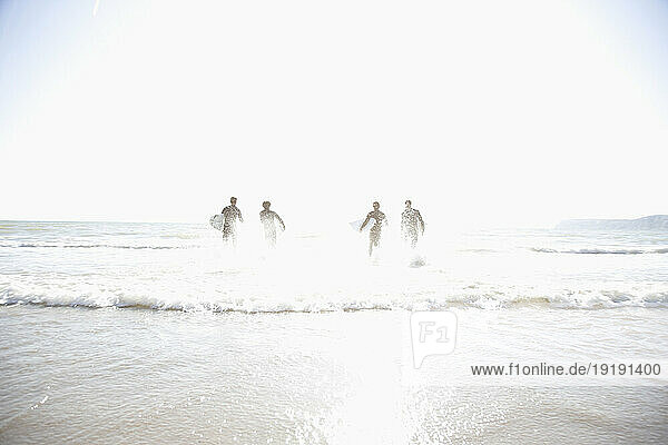 Silhouette of surfers running in the sea