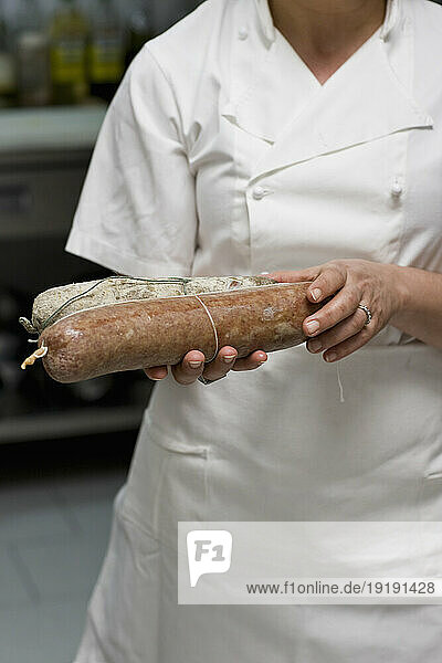 Woman chef holding salami