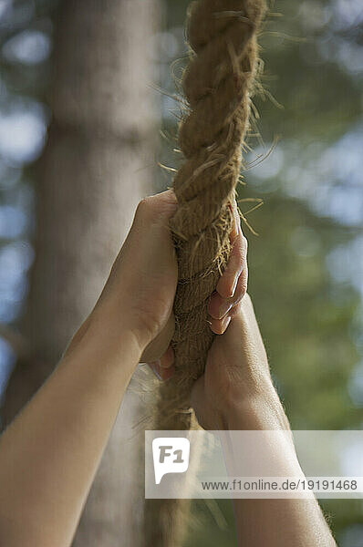 Close up of a woman hands hanging from a rope