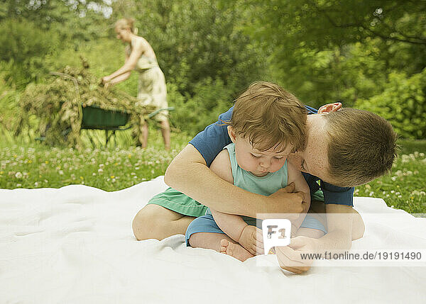 Young boy sitting in a garden embracing a kissing his baby brother