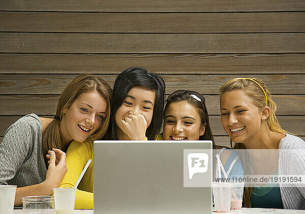 Teenage girls using laptop computer laughing