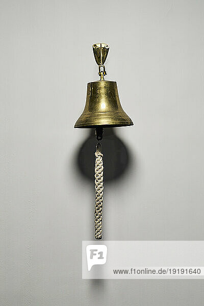 Brass bell with rope pull hanging on wall