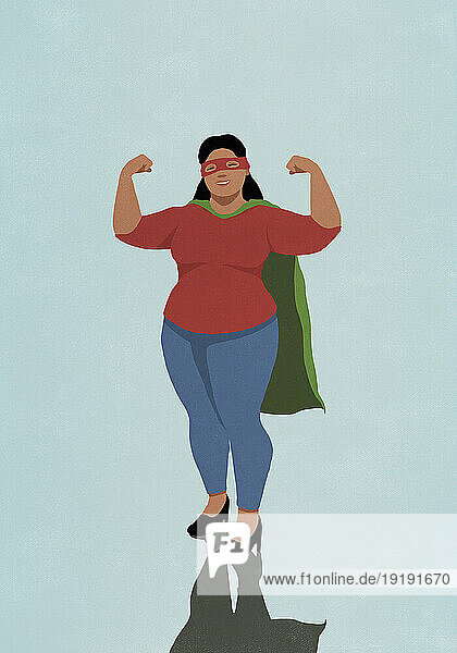 Portrait confident woman in superhero cape flexing biceps