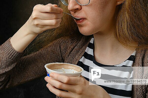 Unbekannte junge Frau mit Brille isst Pudding