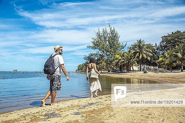 Zwei junge Leute gehen am Strand von Sandy Bay auf der Insel Roatan spazieren. Honduras