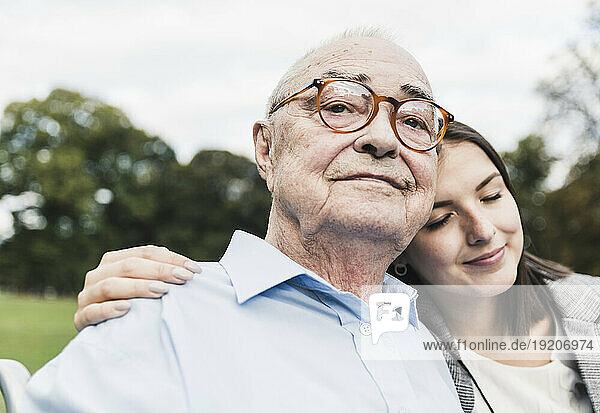 Portrait of self-confident senior man with his granddaughter in a park