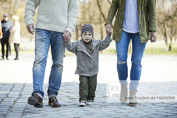 Portrait of boy walking hand in hand with parents