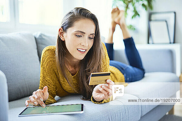 Beautiful smiling woman buying online using tablet and credit card