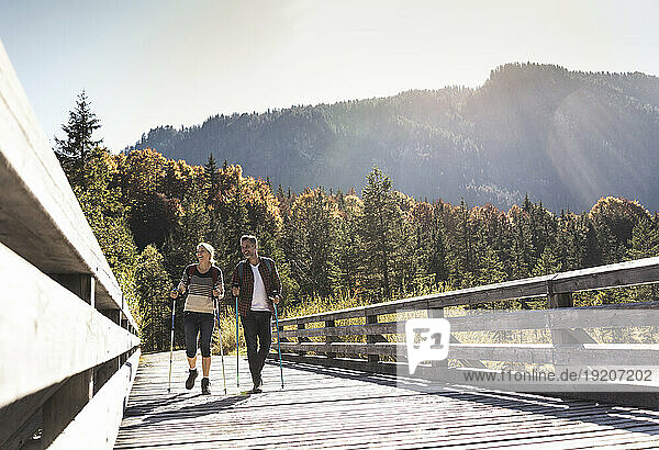 Austria  Alps  Couple crossing bridge walking with hiking poles