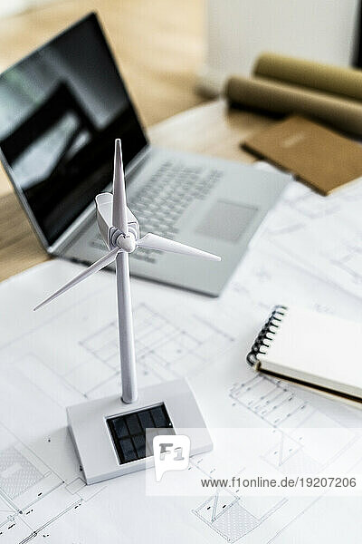 Wind turbine model  construction plan and laptop on table in office
