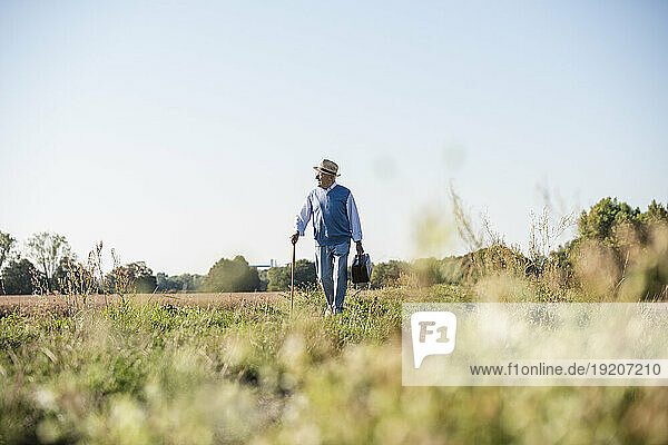 Senior man carrying traveling bag  walking in the fields