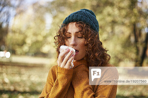 Redhead woman sneezing at autumn park