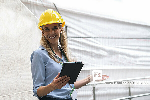 Smiling engineer gesturing holding tablet PC