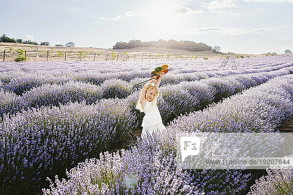 Playful girl holding pinwheel toy in lavender field