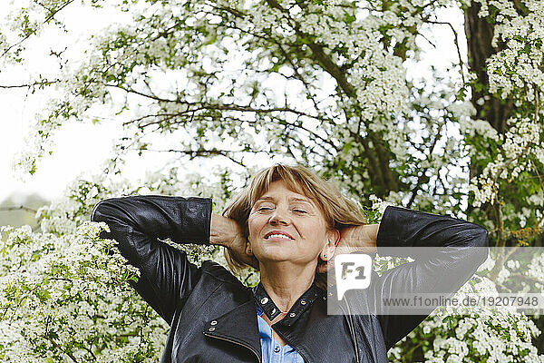 Smiling woman standing under blossoming tree