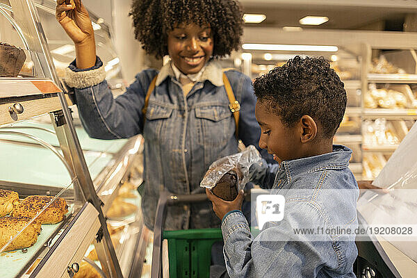 Happy mother with son holding bread in supermarket