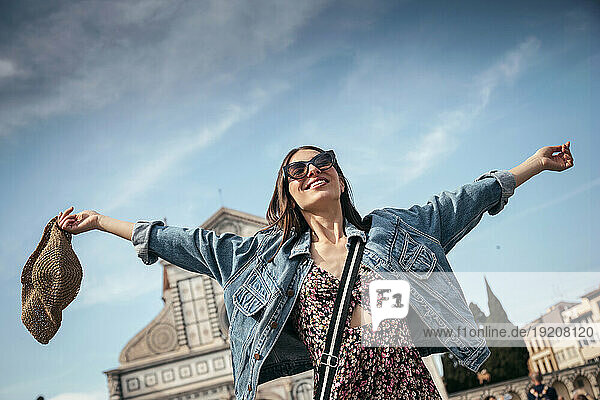 Carefree woman with arms outstretched under sky