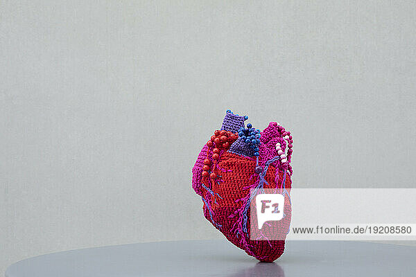 Heart made of wool kept on table against gray background