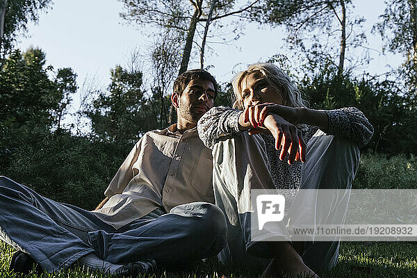 Young couples sitting on grass in meadow at dusk