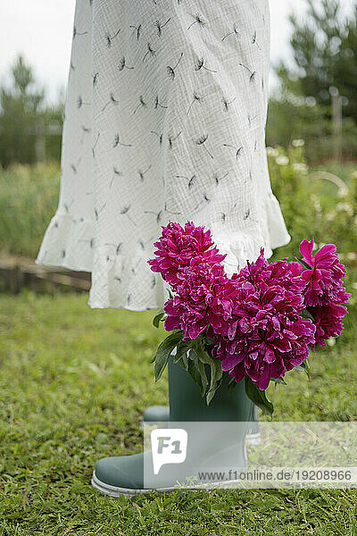 Girl standing with flowers in rubber boot