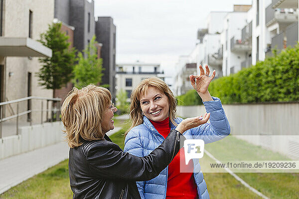 Happy daughter giving key to mother near residential area