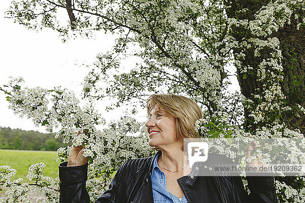 Senior woman standing under blossoming tree
