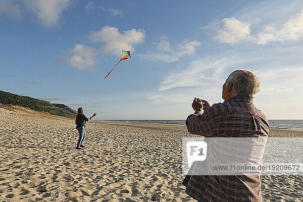 Senior man and woman flying kite at beach