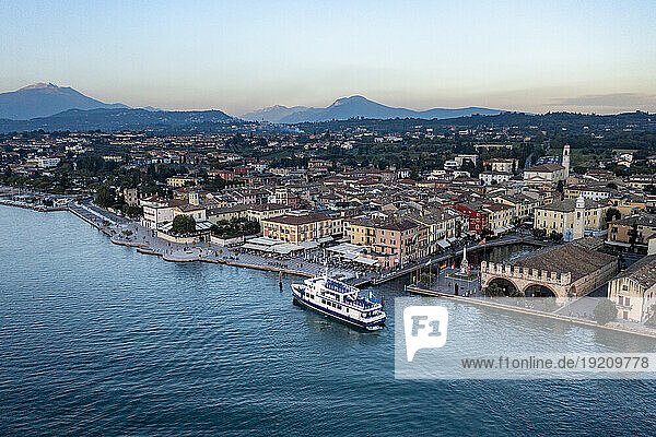 Italy  Veneto  Lazise  Aerial view of lakeshore town with ferry in foreground