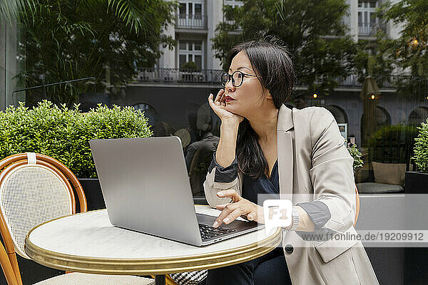 Businesswoman working with laptop on table at sidewalk cafe