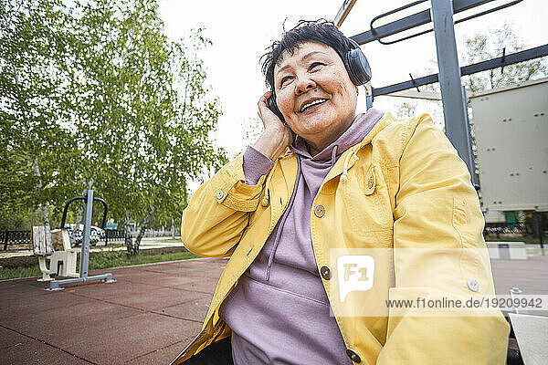 Smiling senior woman listening to music at park