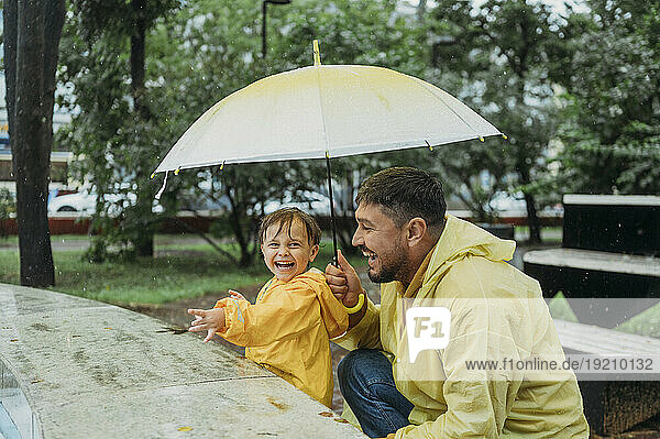 Father and son with umbrella in park