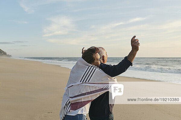 Senior woman hugging man standing at beach