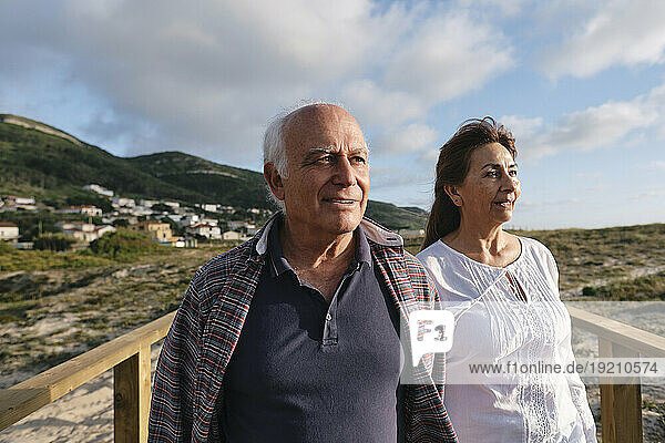 Smiling senior couple on sunny day under cloudy sky