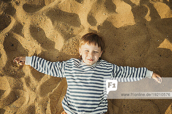 Smiling boy lying on beach sand