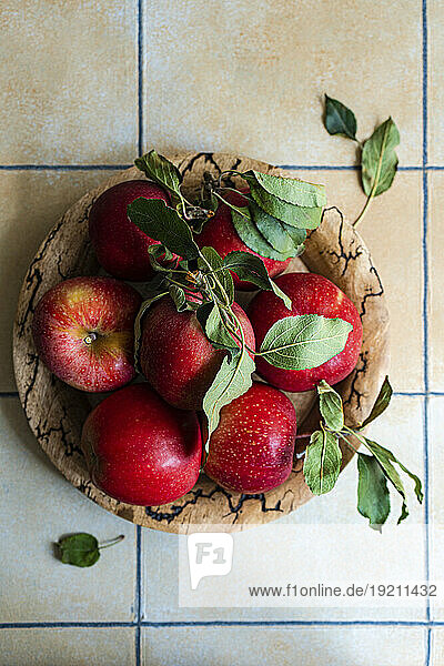 Wooden bowl with red apples on tiled kitchen table