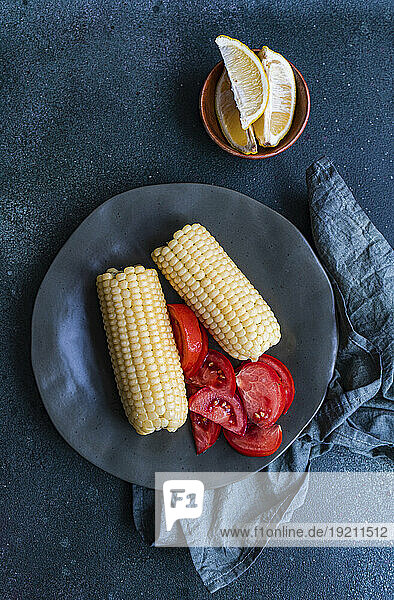Cooked white corn on the cob with tomatoes