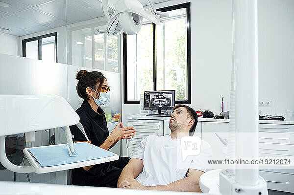 Dentist wearing surgical mask giving advice to patient in examination room
