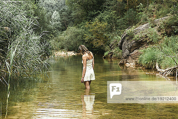 Woman standing in river at forest