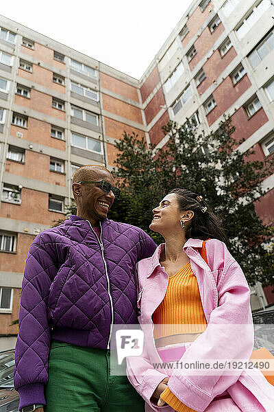 Smiling couple wearing casuals standing in front of building