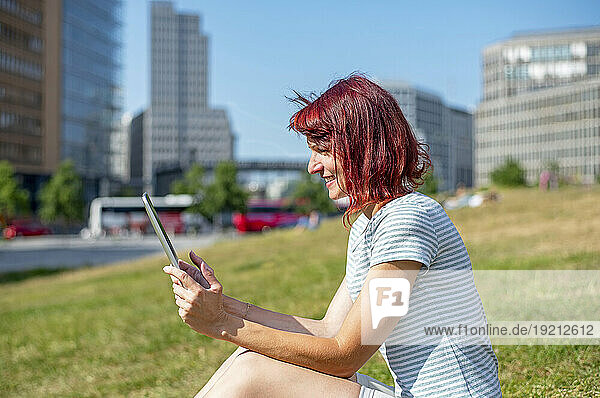 Smiling woman using tablet PC sitting on grass