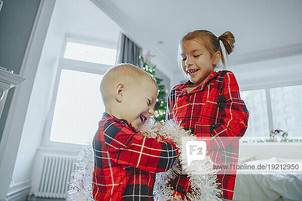 Smiling siblings playing with tinsel sting at home