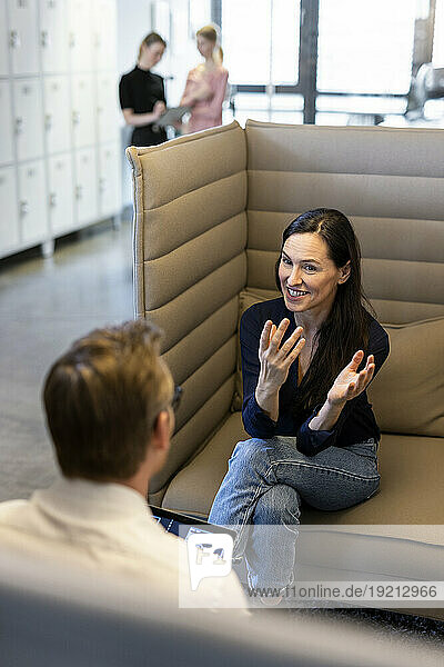 Happy businesswoman gesturing and explaining to colleague at office