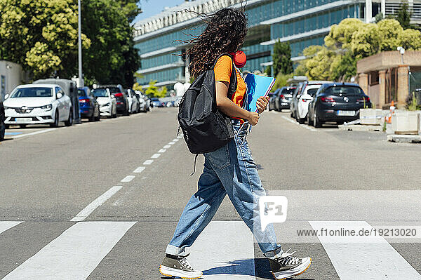 Young student with backpack walking on street in city