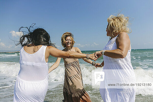 Happy women enjoying together near wavy sea at beach
