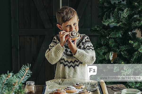Boy eating cinnamon bun at table